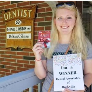 A woman holding up her dental card outside of the dentist.