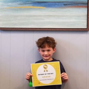 A boy holding up a sign in front of a painting.