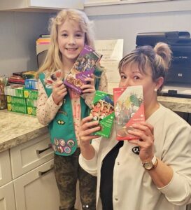 A woman and girl holding up boxes of cookies.