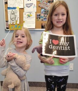 Two girls holding a sign and some tooth brushes