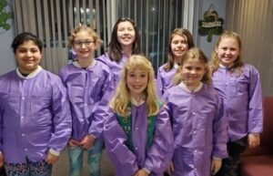 A group of girls in purple jackets posing for the camera.