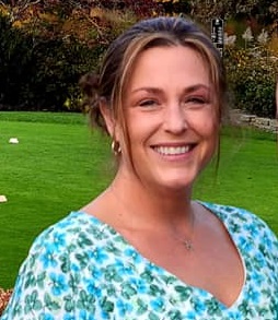 A woman standing in front of some grass.