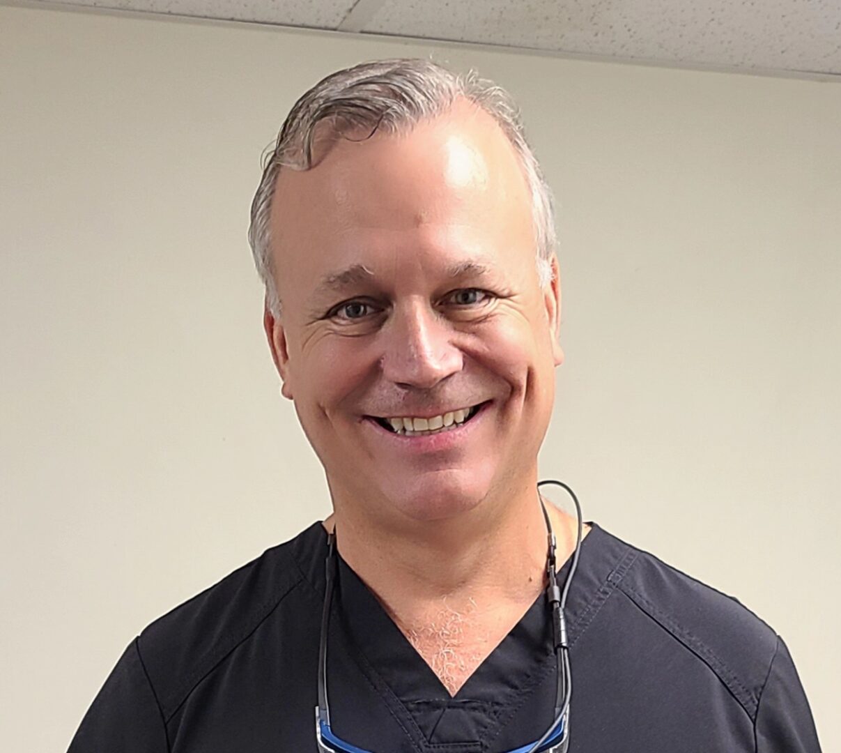 A man with grey hair and glasses smiles for the camera.