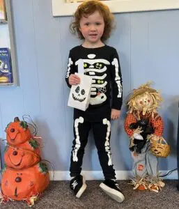 Young girl in skeleton costume holding a bag