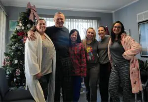 Group of friends posing by Christmas tree.