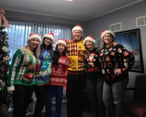 Group wearing festive Christmas sweaters.