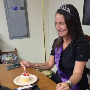 Woman celebrating birthday with cupcake.