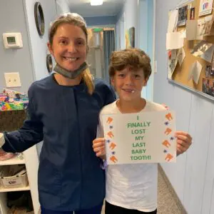 Boy holding a sign, lost his last baby tooth.