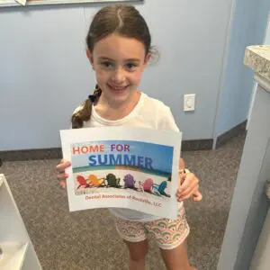 Girl holding "Home for Summer" sign.