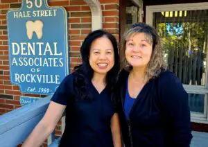 Two women smiling in front of dental office.