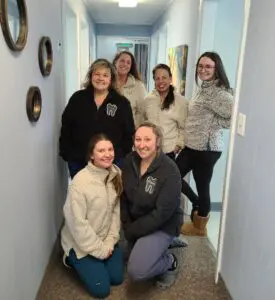 Dental staff smiles in hallway.